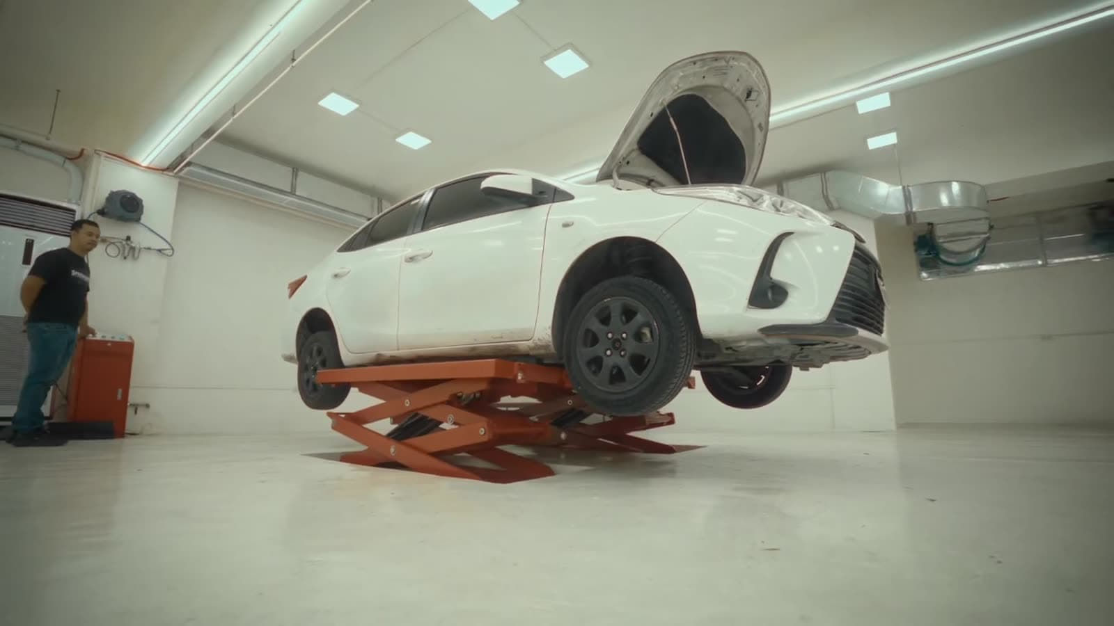A white car raised on a scissor lift in the shop